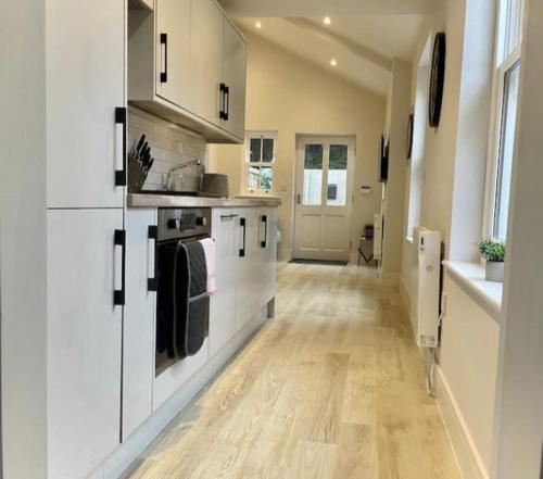 a kitchen with white cabinets and a wooden floor at Moat View FREE PARKING, CENTRAL, EV PLUG in York