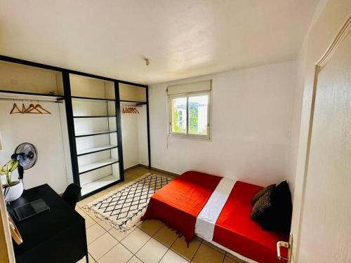 - une chambre avec un lit rouge et une fenêtre dans l'établissement Appartement Badja, à Tsingoni