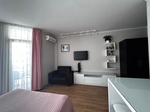 a living room with a television and a couch and a chair at Black Sea Apartament in Batumi