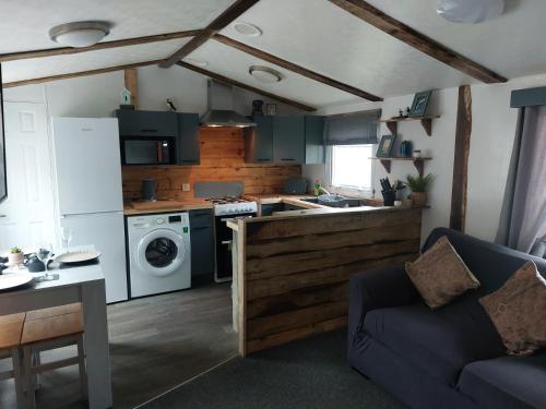 een keuken en een woonkamer met een bank en een fornuis bij The Gull & Puffin Cresswell in Cresswell