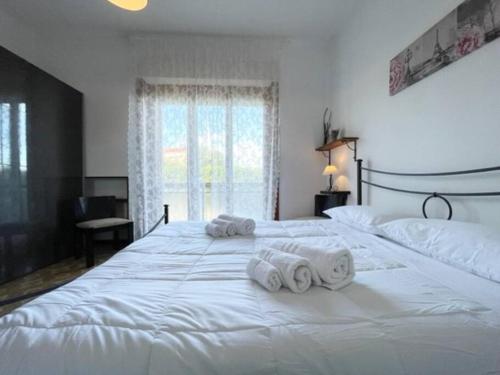 a bedroom with two large white beds with towels on them at [Loano 2] parcheggio privato - wifi- giardino in Loano