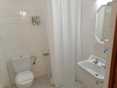 a white bathroom with a toilet and a sink at Hostal Pepe in San Ferrán de ses Roques