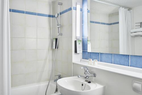 La salle de bains est pourvue d'un lavabo et d'une douche. dans l'établissement Kyriad Direct Le Havre Est - Gonfreville, à Gonfreville-l'Orcher
