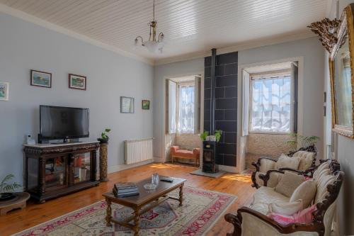 a living room with a couch and a tv at Casa do Hospital-Guest House in Abaças
