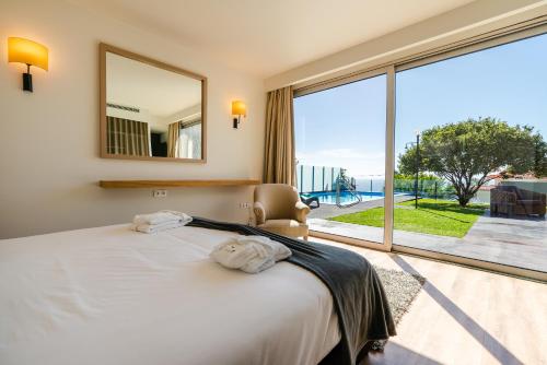a bedroom with a bed and a large window at Calheta Tangerine House in Arco da Calheta