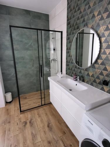 ein Bad mit einer Dusche, einem Waschbecken und einem Spiegel in der Unterkunft Apartament Jezioro w sercu Ostródy in Ostróda