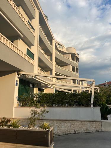 a large white building with plants in front of it at Apartman Ambasador in Makarska