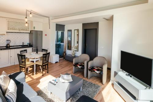 a living room with a couch and a tv and a kitchen at Calheta Tangerine House in Arco da Calheta