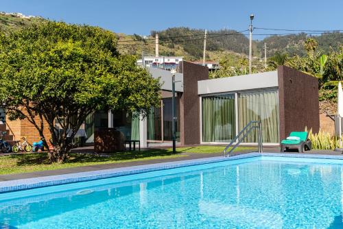 a swimming pool with a slide in front of a house at Calheta Tangerine House in Arco da Calheta