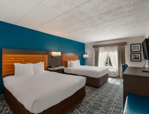 a hotel room with two beds and a desk at Comfort Inn Falls Church - Tysons Corner in Falls Church
