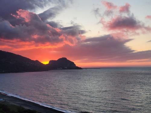 a sunset over the ocean with a mountain at Beach of Eden Cefalu' in Cefalù