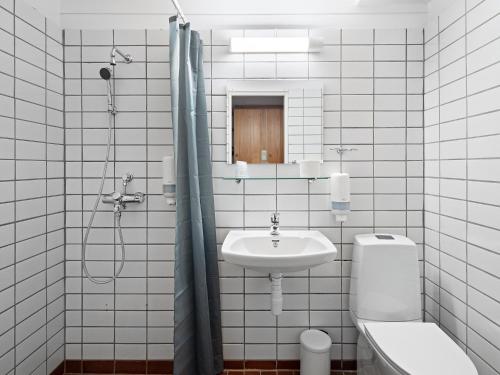 a white tiled bathroom with a sink and a toilet at Eidfjord Hotel in Eidfjord