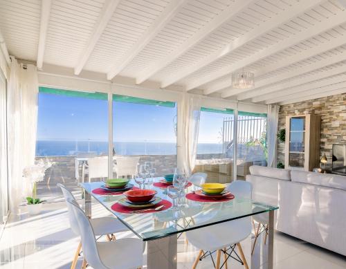 a dining room with a glass table and white chairs at Penthouse of Views Los Cristianos in Los Cristianos