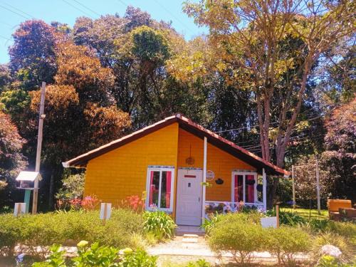 una pequeña casa amarilla con una puerta blanca en Hospedaje Santaelena -chalets de montaña-, en Santa Elena