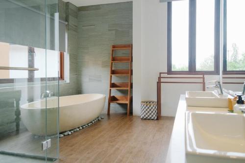 a bathroom with a large tub and two sinks at Villa Maisha by The Lavana in Nusa Dua