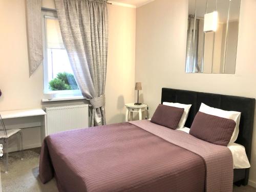 1 dormitorio con 1 cama con manta morada en Lacona, en Stąporków