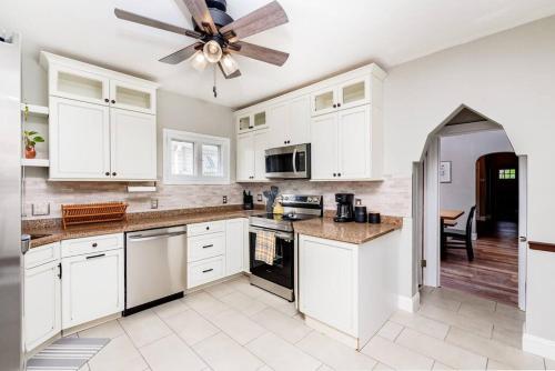 a kitchen with white cabinets and a ceiling fan at Cozy Family Cottage - Historic Top of The Hill in Tower Grove