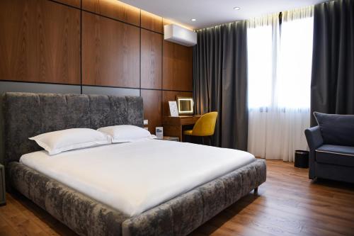 - une chambre avec un grand lit et une chaise dans l'établissement The Wilson Tirana, à Tirana