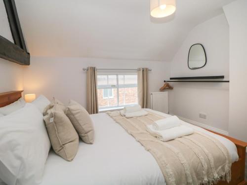a bedroom with a large white bed with a window at Kennedy's Cottage in Ashbourne