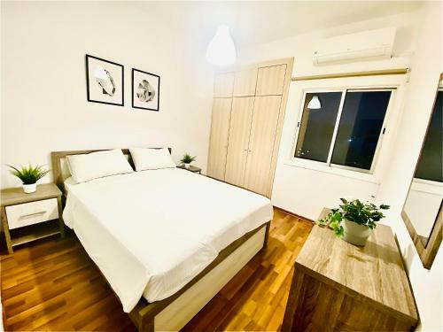 ein Schlafzimmer mit einem großen weißen Bett und einem Fenster in der Unterkunft CHADI APARTMENT in Larnaka