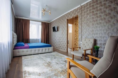 ein Schlafzimmer mit einem Bett, einem Stuhl und einem Sofa in der Unterkunft 1-комнатная квартира в центре на Аль-Фараби 93 in Qostanai