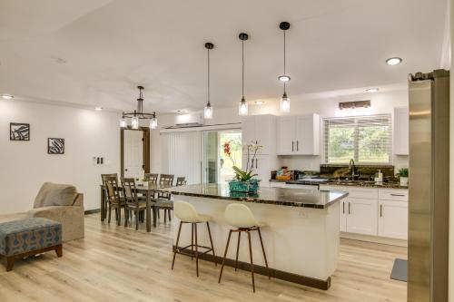 a kitchen and living room with white cabinets and a table at Keaau Getaway with Patio, 3 Mi to Shipman Beach! in Keaau