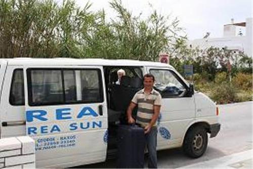 a man standing in front of a van with a suitcase at Hotel Rea in Naxos Chora