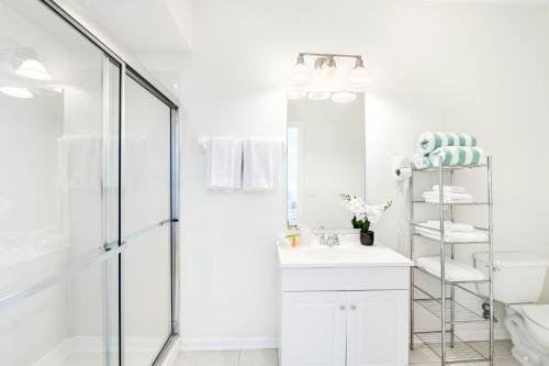 ein weißes Bad mit einer Dusche und einem Waschbecken in der Unterkunft Beautiful Newly Updated Townhome Sleeps 10 in Orlando