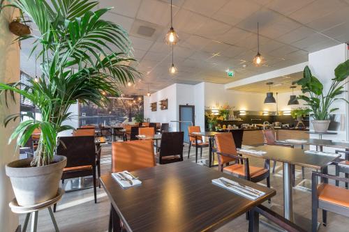 un restaurante con mesas, sillas y macetas en Leonardo Hotel Utrecht City Center, en Utrecht