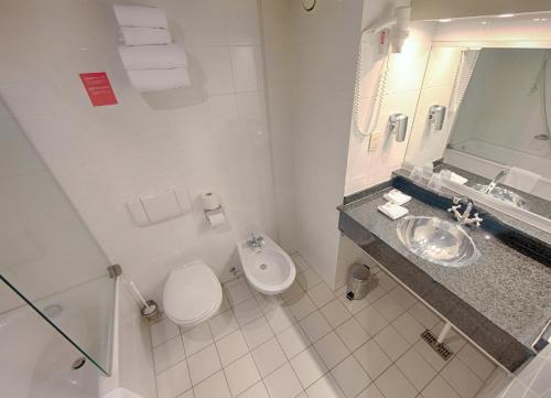 La salle de bains blanche est pourvue de toilettes et d'un lavabo. dans l'établissement Leonardo Hotel Utrecht City Center, à Utrecht
