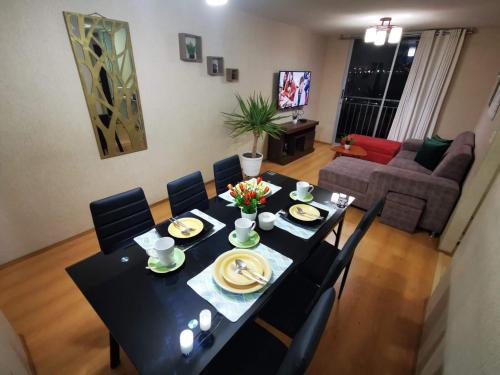 una mesa de comedor negra con sillas y platos de comida en Hermoso departamento en condominio, en Tacna