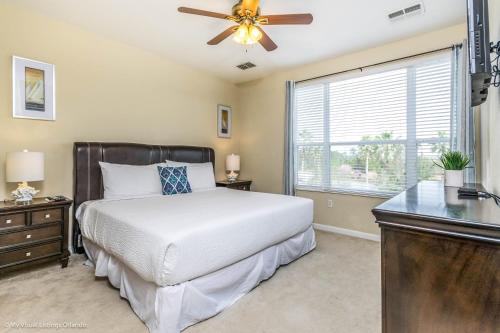 a bedroom with a bed with a ceiling fan and a window at Spacious Vista Cay Townhome Newly Furnished in Orlando