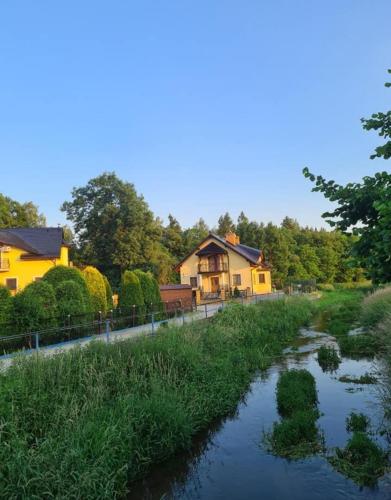a river in front of a house and a house at MARMI Noclegi in Golczowice