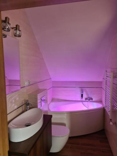 ein Badezimmer mit einer Badewanne mit rosafarbener Beleuchtung in der Unterkunft MARMI Noclegi in Golczowice