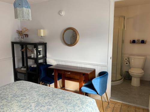 a bedroom with a table and blue chairs and a bathroom at Maison Charles Edmond in Grandes-Bergeronnes