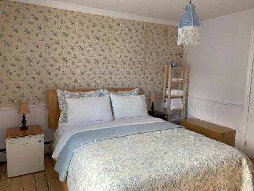 a bedroom with a bed with a blue and white blanket at Maison Charles Edmond in Grandes-Bergeronnes