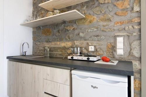 cocina con pared de piedra y encimera en Dreamy Cycladic Summer House 3, en Serifos Chora