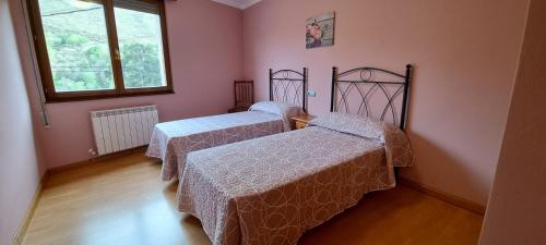 two beds in a room with pink walls at Llanes-Llumedian in Llanes