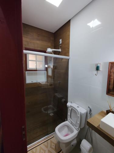 a bathroom with a toilet and a glass shower at Pouso Casa da Vovó in Tiradentes