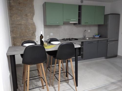una cocina con armarios verdes y una mesa con taburetes. en Apartman Lari, en Vižinada