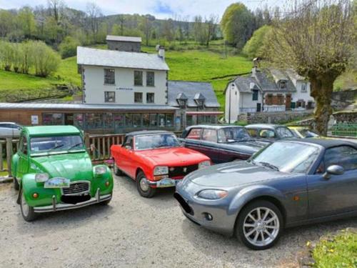 un groupe de voitures garées sur un parking dans l'établissement Auberge du Pont, à Saint-Projet-de-Salers
