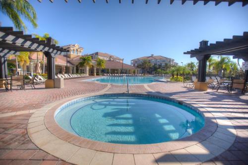 a swimming pool in a resort with tables and chairs at Resort Townhome: Perfect Orlando Vacation Spot in Orlando