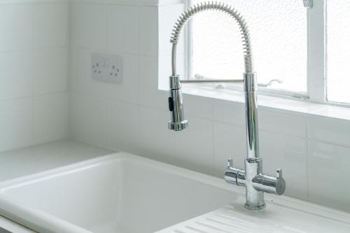 - un évier avec un robinet dans une cuisine blanche dans l'établissement Bright West Hampstead Retreat, à Londres