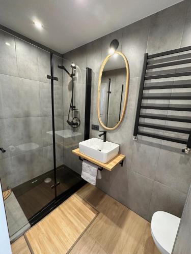 a bathroom with a sink and a shower and a mirror at Apartamenty Kowalska in Kościerzyna