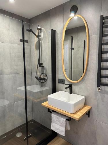 a bathroom with a sink and a shower and a mirror at Apartamenty Kowalska in Kościerzyna