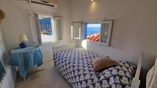 a bedroom with a bed and a table and two windows at Peppermint Bay in Skopelos Town
