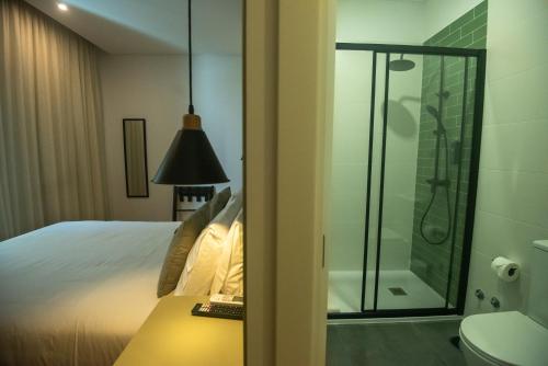 uma casa de banho com uma cama e uma cabina de duche em vidro em Olive Boutique Guesthouse em Vila Franca do Campo
