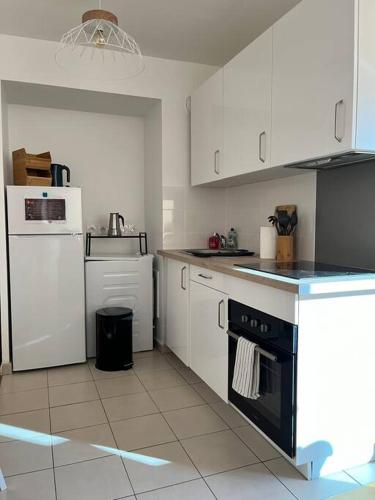 a kitchen with white cabinets and a black oven at Superbe Appart 2P pour 4 pers à 5 min TGV RER Orly in Massy