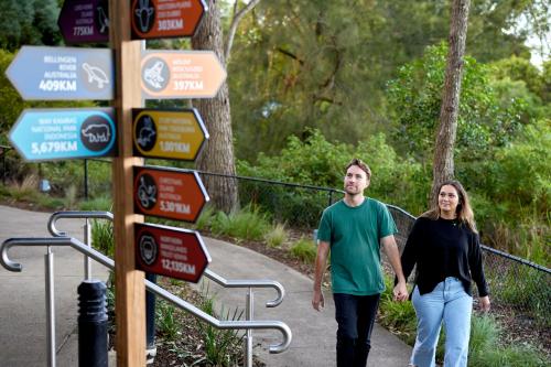 a man and a woman walking down a path with signs at Roar And Snore in Sydney