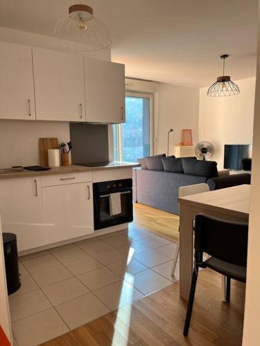 a kitchen and living room with white cabinets and a couch at Superbe Appart 2P pour 4 pers à 5 min TGV RER Orly in Massy